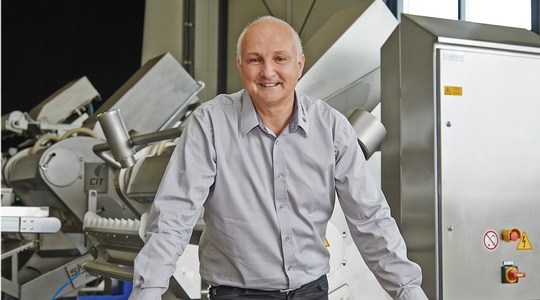 lächelnder Mann im Hemd  vor einer Maschine der Insort GmbH